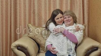 母亲坐在椅子上，女儿拥抱。 两个女人说说笑笑.. 两个美丽的女孩拥抱着母亲和女儿